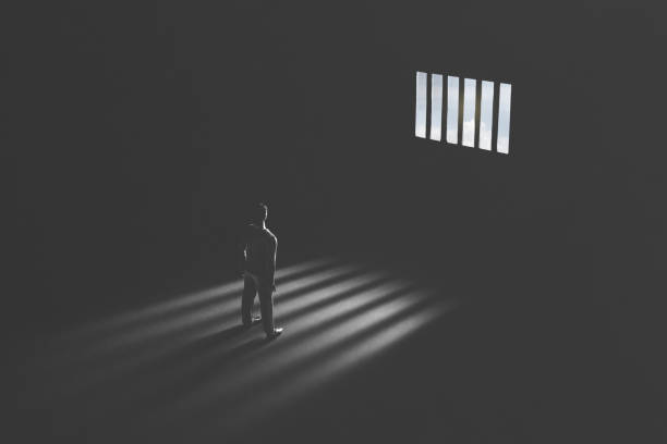 A figure shut in a dark room, light only through a barred window